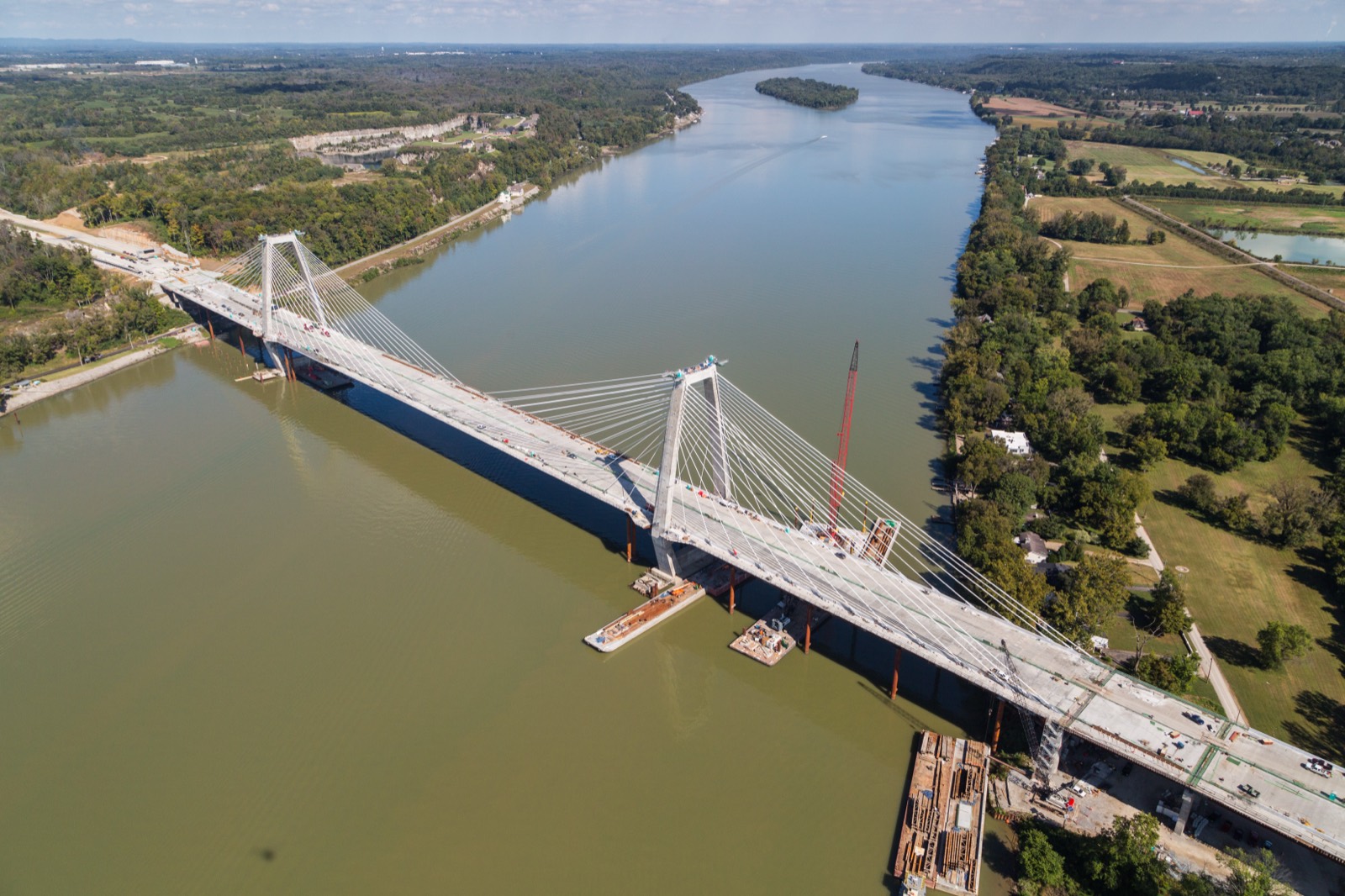 Aerial view of a cable-stayed bridge under construction across a wide river